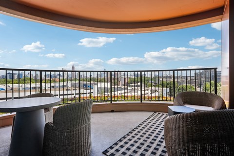 A balcony with a table and chairs overlooking a cityscape.