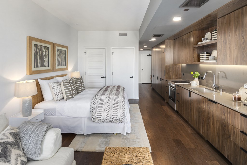 a bedroom with a bed and a kitchen in a 555 waverly unit