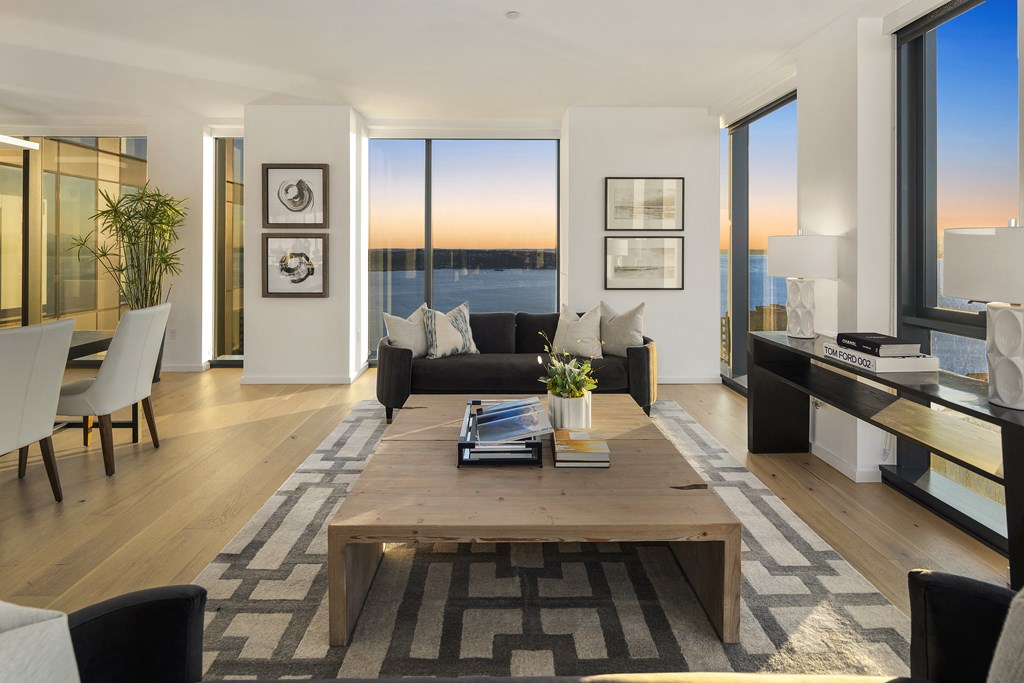 a living room with a large wooden coffee table and a large window with a view of the