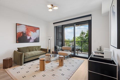 A living room with a green couch and a painting on the wall.