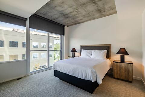 A bedroom with a large bed and a window overlooking a building.
