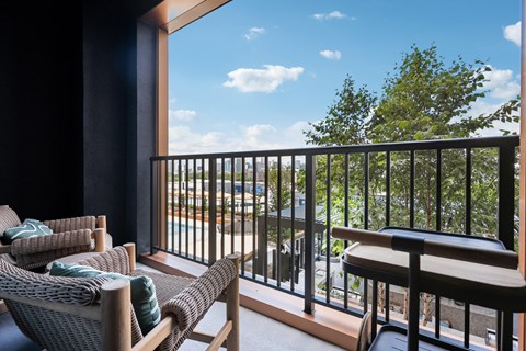 A balcony with a chair and a table overlooking a street.