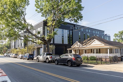 A street with cars parked on the side and a building in the background.