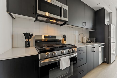 A modern kitchen with a black stove top oven and black cabinets.