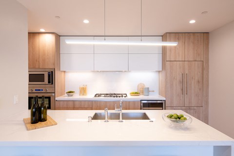 a modern kitchen with white countertops and wooden cabinets