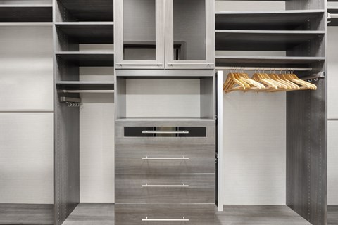 A wooden hanger is holding a white shirt on a clothes rack.