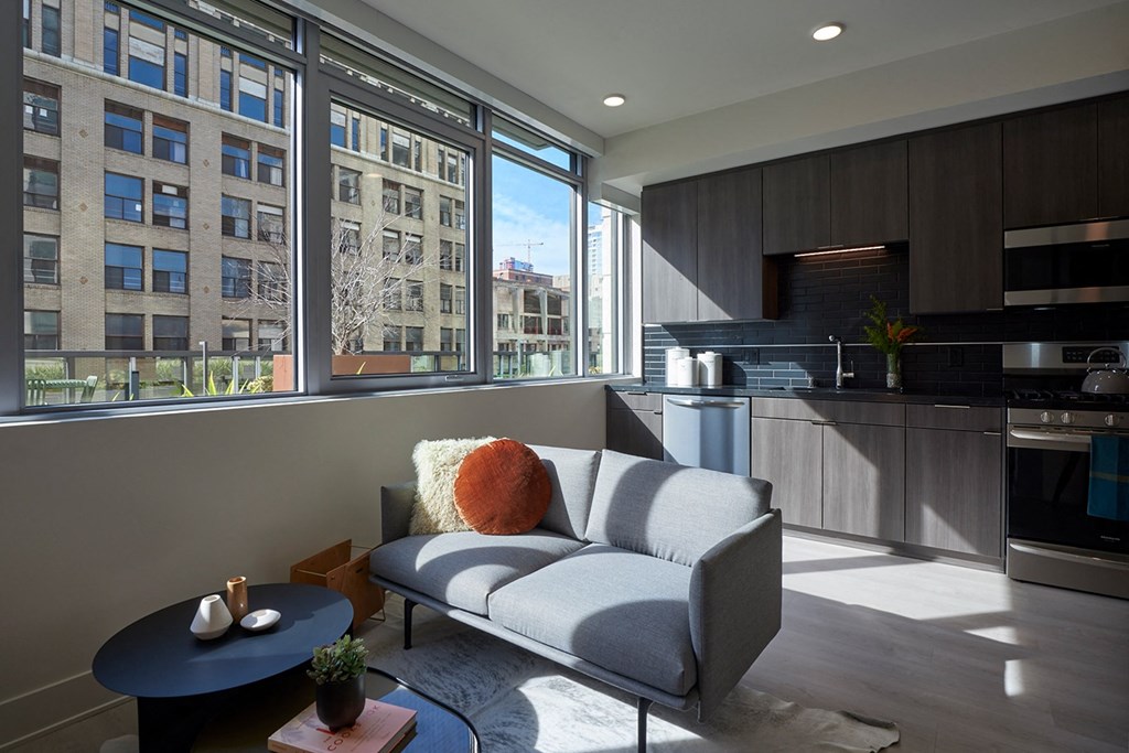 a living room with a couch and a kitchen with a large window