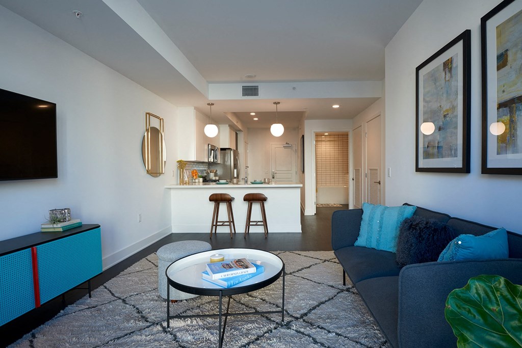 a living room with a couch and a coffee table in front of a kitchen