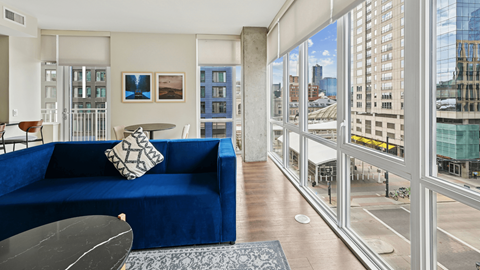 A blue couch sits in a living room with a view of the city.