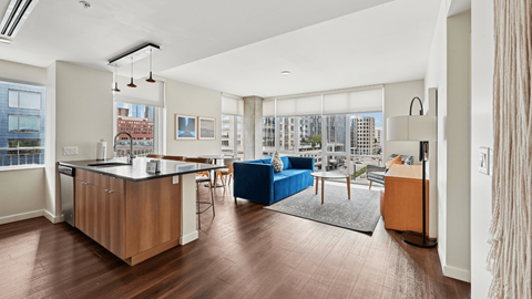 A modern kitchen with wooden floors and a blue sofa.