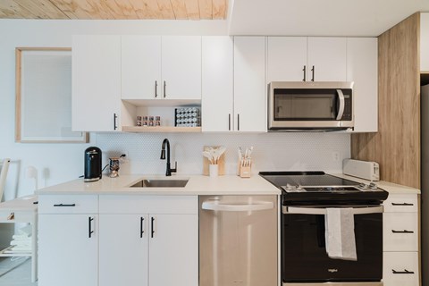 A modern kitchen with white cabinets and a black oven.