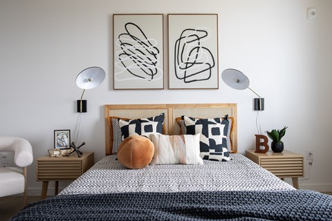 A bedroom with a bed, two lamps, and a chair.