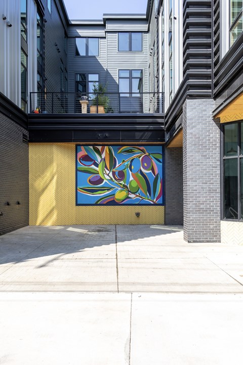 A mural of a colorful flower is painted on a yellow wall.