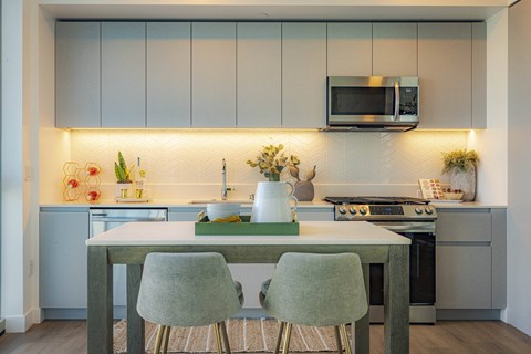 a kitchen with white cabinets and a table with three chairs