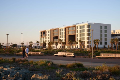 A man and woman are walking in front of a modern building.
