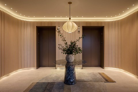 A modern hallway with a round table and a hanging lamp.
