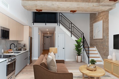 A living room with a couch, a table, and a staircase.