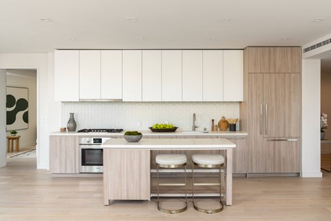 a kitchen with white cabinets and a white island with three stools