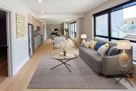 A modern living room with a grey sofa and a glass coffee table.