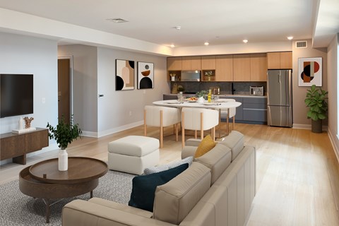 A modern living room with a white couch, a coffee table, and a kitchen in the background.
