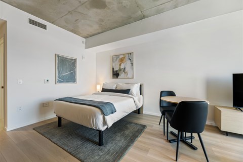 A bedroom with a bed, chair, and painting on the wall.