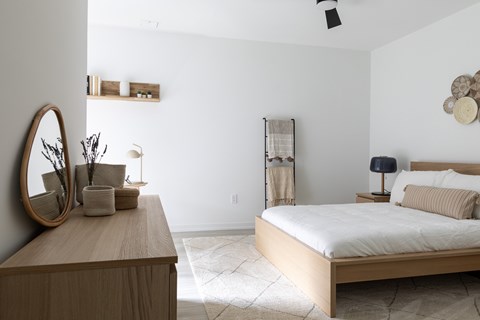 A bedroom with a bed, nightstand, and a mirror on the dresser.