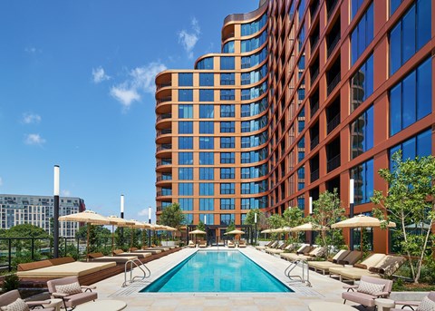 A large pool surrounded by lounge chairs and umbrellas in front of a tall building at Stella at Star Metals in West Midtown, Atlanta.
