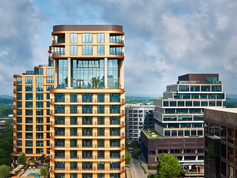 A tall building with a curved top is surrounded by other buildings at Stella at Star Metals in West Midtown, Atlanta.