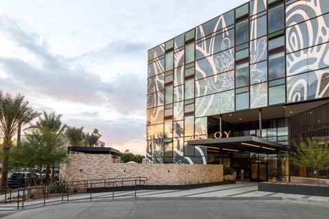 A modern building with a glass facade and a stone wall in front.