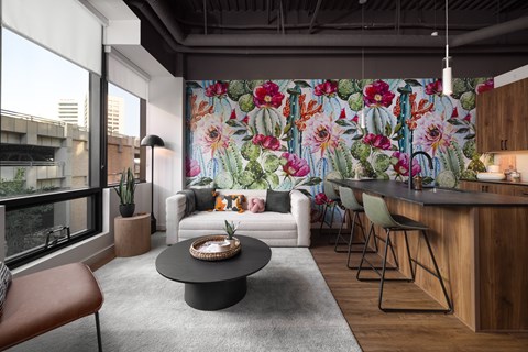A modern living room with a large floral wallpaper and a wooden bar area.