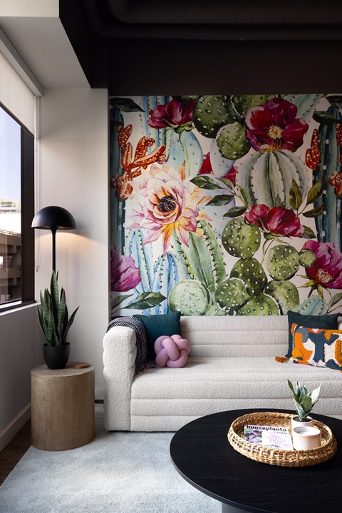 A living room with a couch, a table, and a cactus.