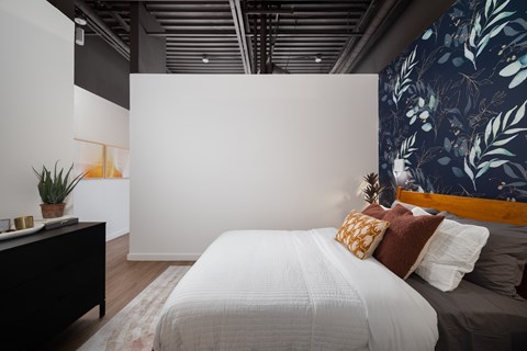 A bedroom with a white bed and a plant on the nightstand.