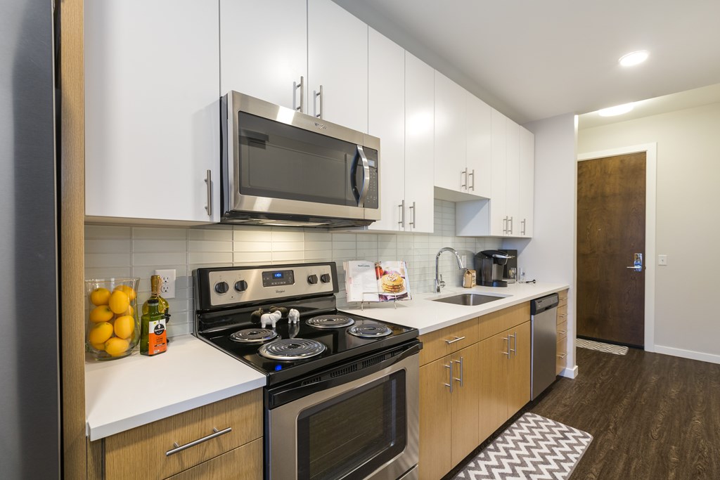 A modern kitchen with a black stove top oven and white countertops.