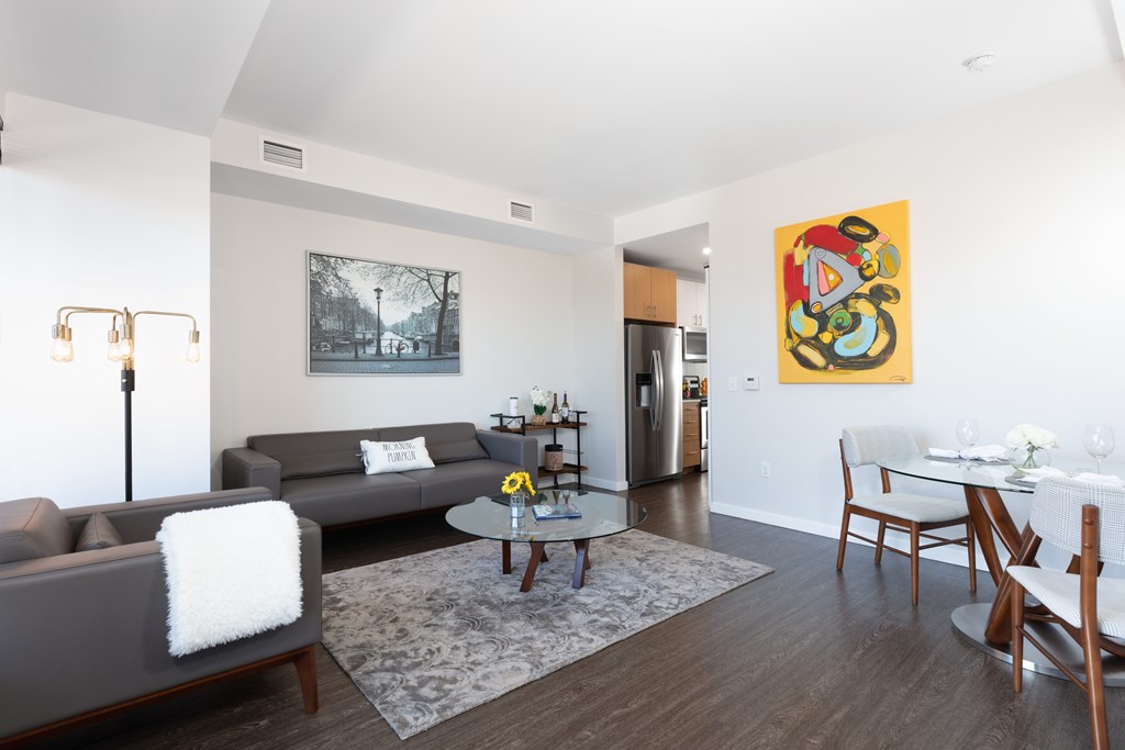A living room with a grey couch and a painting on the wall.