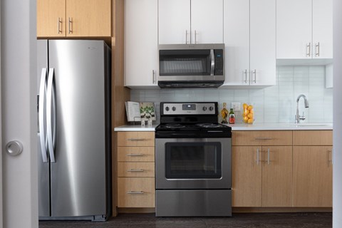 A modern kitchen with a stainless steel refrigerator and a black stove top oven.