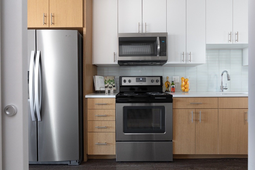 A modern kitchen with a stainless steel refrigerator and a black stove top oven.