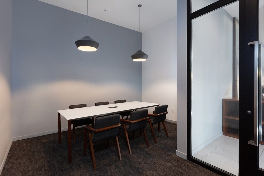 A conference room with a white table and black chairs.