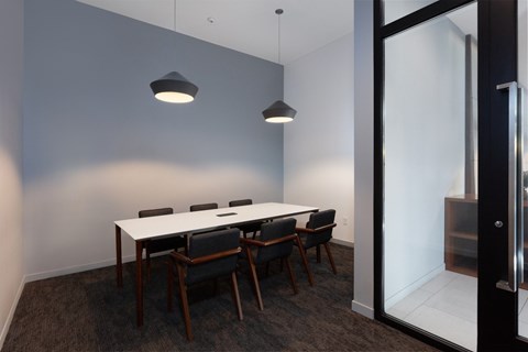 A conference room with a white table and black chairs.