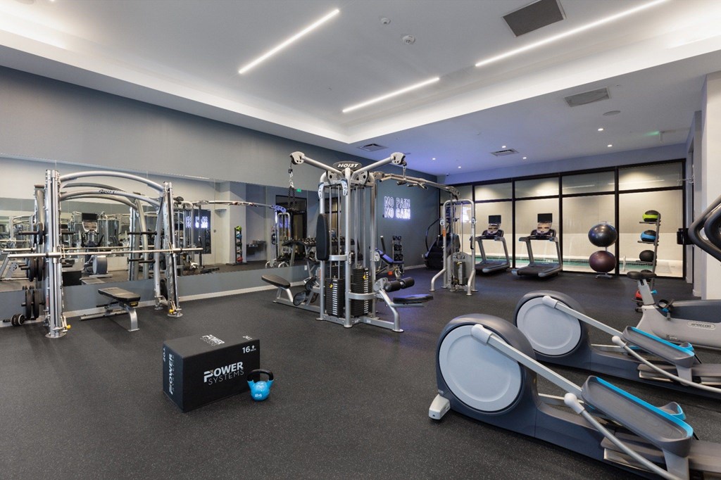A gym with a variety of equipment including treadmills, weights, and exercise machines.