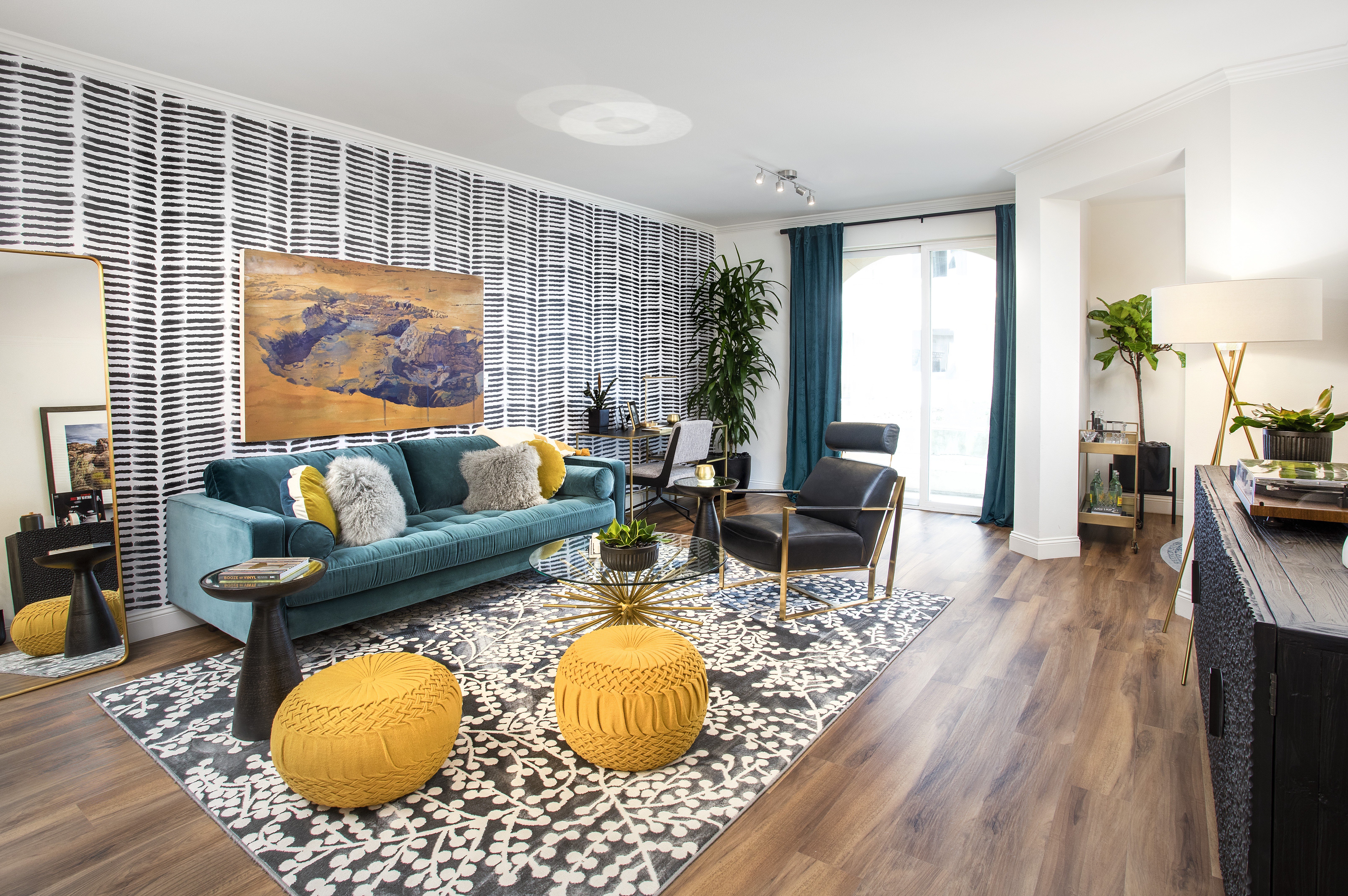A living room with a blue couch and a painting on the wall.