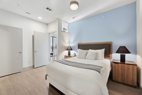A bedroom with a large bed and a wooden nightstand.