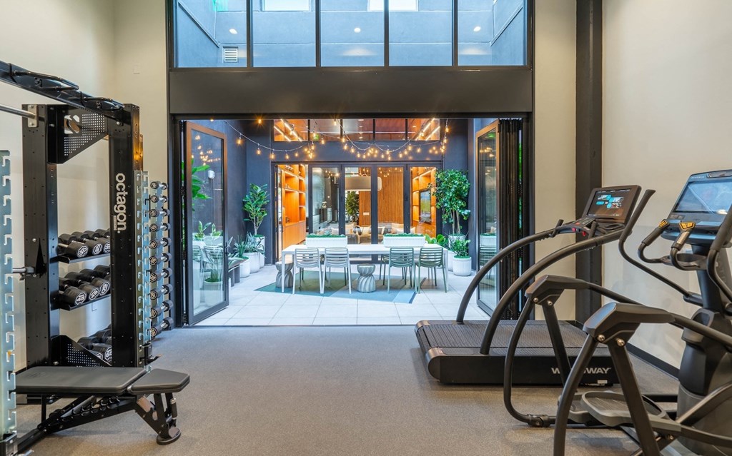 a gym with exercise equipment and a patio with tables and chairs