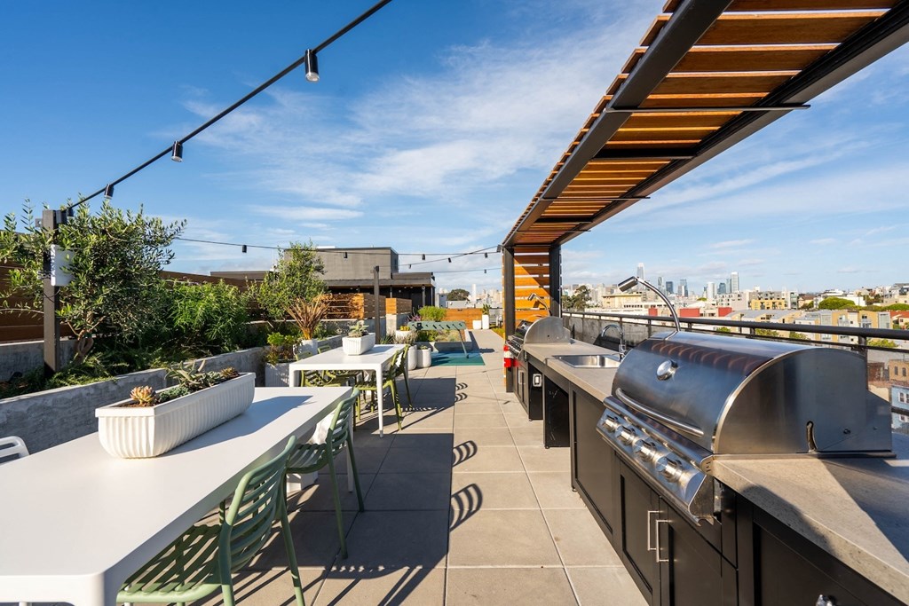 the rooftop patio has a barbecue grill and tables with chairs