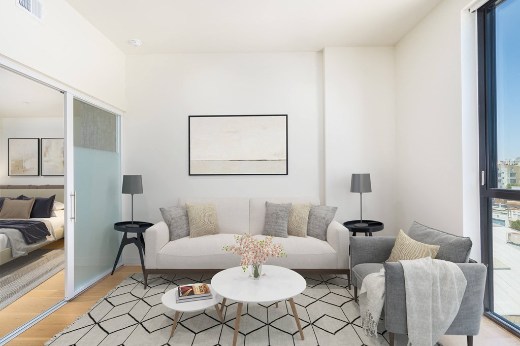 a living room with a white couch and a white coffee table with a vase of flowers