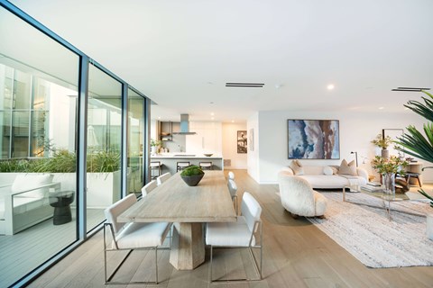 A modern dining room with a wooden table and white chairs.