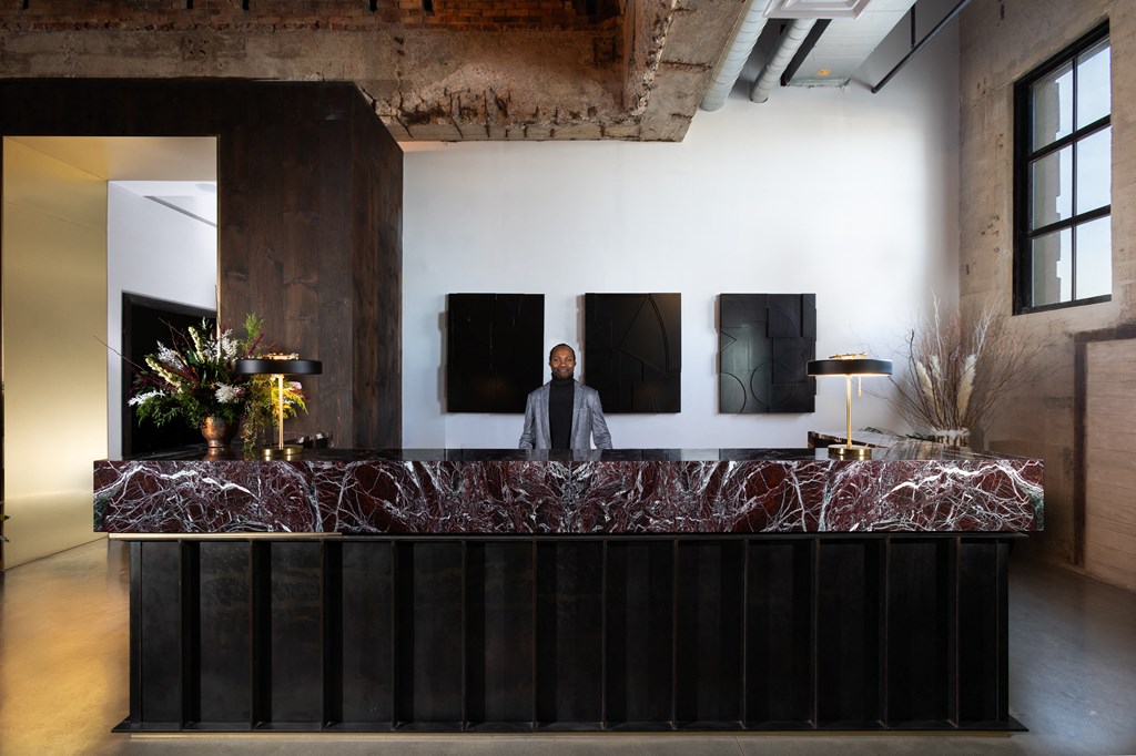 a man stands at a reception desk in a lobby with a marble counter top