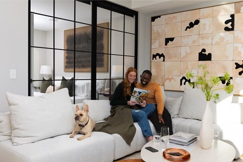 a man and woman sitting on a couch in a living room with a dog