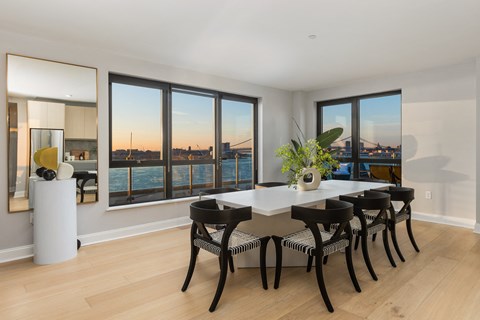 a dining room with a table and chairs and a view of the water