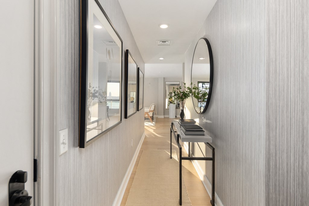 a hallway with a large mirror on the wall and a table with a black stool