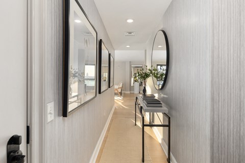 a hallway with a large mirror on the wall and a table with a black stool
